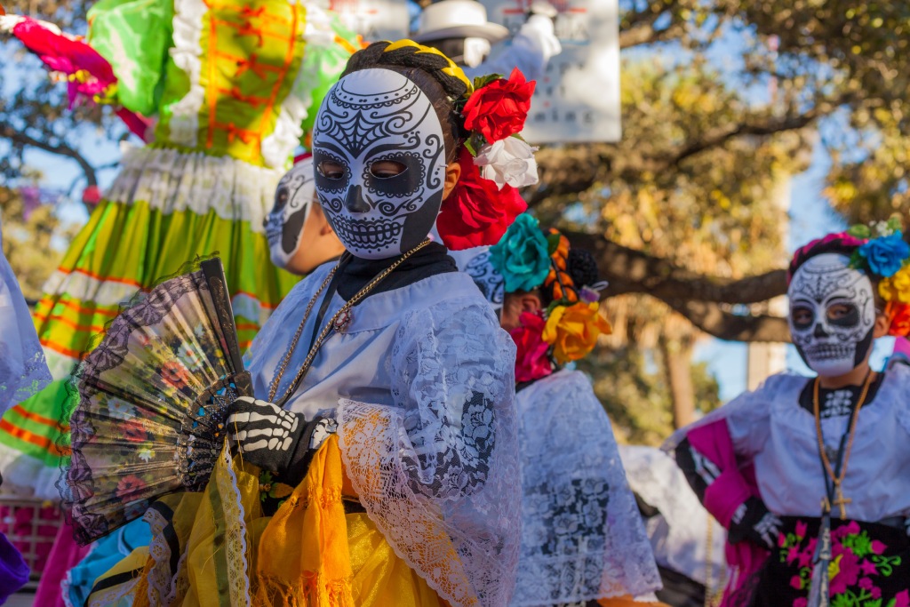 Group of unrecognizable women wearing traditional sugar skull masks and costumes for Dia de los Muertos celebration